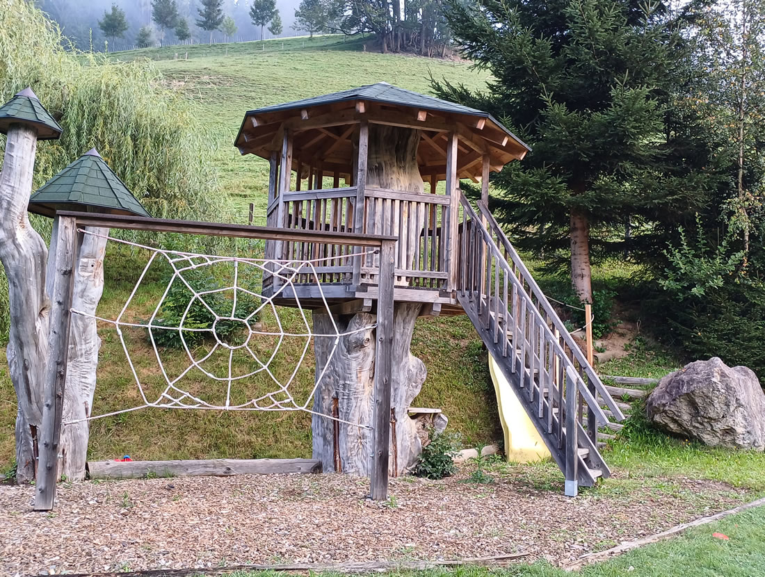 Natürlicher Spielplatz für Kinder mit Kletterturm und weiten Wiesen